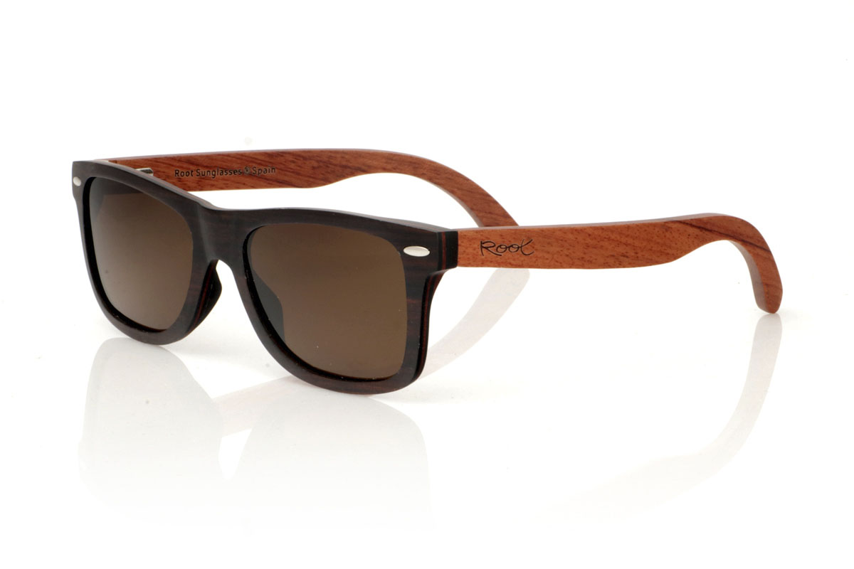 Wood eyewear of Ebony OSCAR. Gafas de sol de madera OSCAR, destaca su estilo inspirado en los clásicos, ofreciendo una silueta ancha que capta la atención. Estas gafas están meticulosamente fabricadas en capas de madera laminada, combinando ébano en el exterior y caoba en el centro, creando un efecto visual único y elegante, realzado por remaches plateados en el frontal. Las varillas de caoba prometen no solo estilo, sino también una durabilidad excepcional. Además de su diseño impecable, las OSCAR garantizan una visión clara y una protección total, asegurando que tus ojos estén protegidos con el máximo confort. Medidas: 149x45 mm. Calibre: 54. Con las OSCAR, experimentarás la perfecta unión entre moda y funcionalidad. for Wholesale & Retail | Root Sunglasses® 